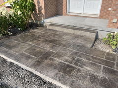 Stamped concrete walkway and steps leading to a front door with brick exterior and surrounding landscaping.