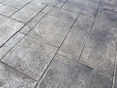 Gray stamped concrete surface with a textured pattern resembling stone tiles.