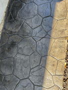 Stamped concrete walkway with irregular stone pattern and color variation from dark gray to tan.