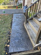 Stamped concrete walkway leading to wooden porch steps of a house