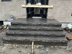 Freshly poured and textured concrete steps and landing at a residential front entrance with brick exterior walls.