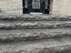 Stamped concrete steps with textured risers leading to a front entrance with black double doors and brick walls