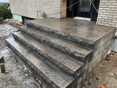 Stamped concrete steps and landing at a front entrance of a brick house