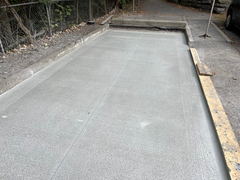 Freshly poured concrete driveway section with control joints and adjacent curb area