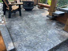 Stamped concrete patio with wooden chairs, fire pit, and wooden steps