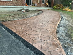 Curved stamped concrete walkway with hexagonal pattern leading to a brick house entryway