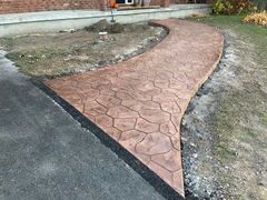 Curved stamped concrete walkway with hexagonal pattern leading from asphalt driveway to house entrance