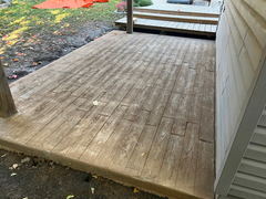 Stamped concrete patio with wood plank pattern next to house and steps leading to yard