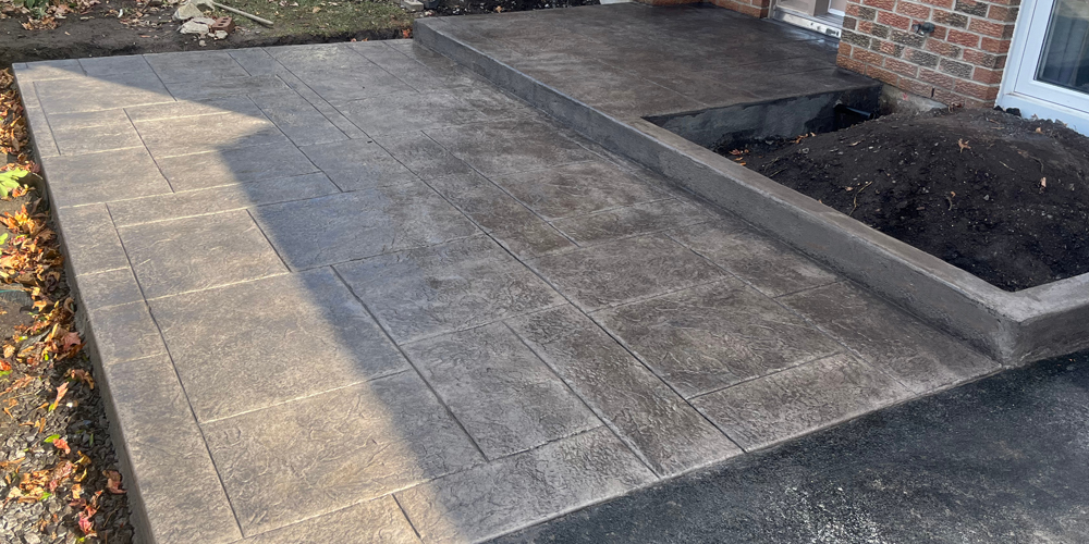 stamped concrete front walkway with step and garden walls in smoke grey